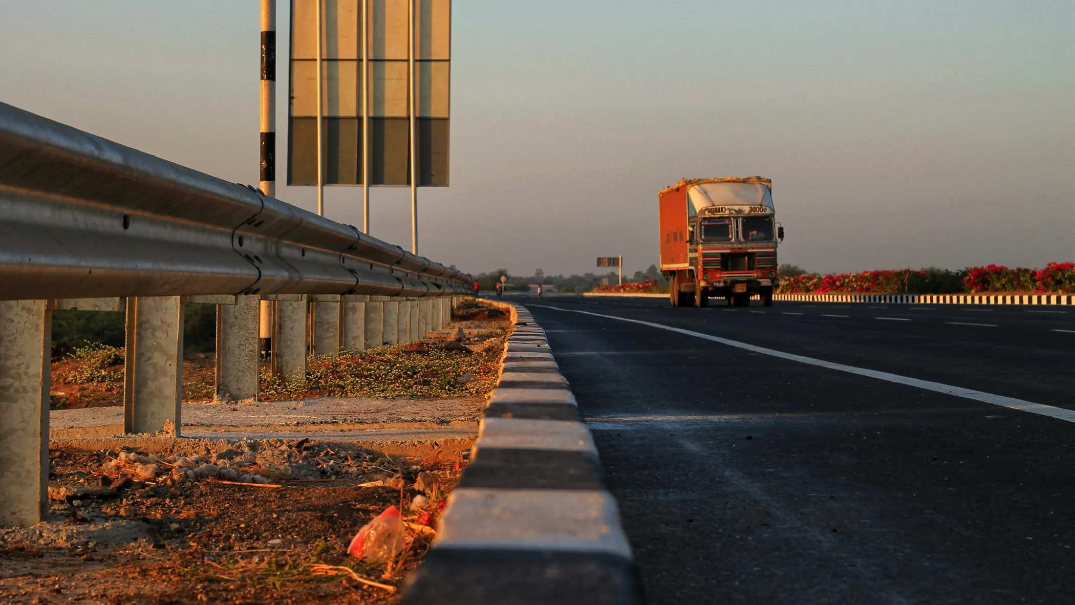 Caminhão laranja na rodovia ao entardecer